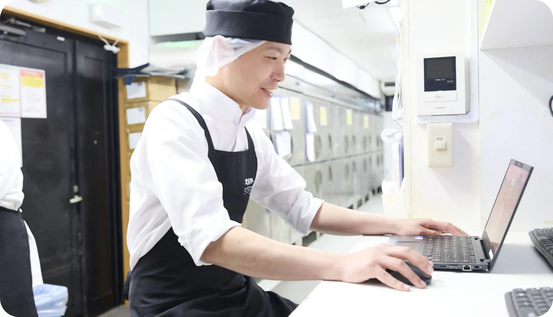 バックヤードでノートパソコンに向かう佐藤圭介